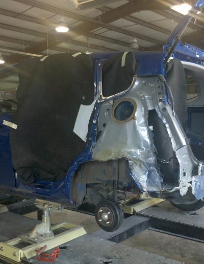 A badly damaged blue van being repaired