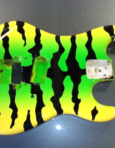 A custom painted guitar with bright yellow and green paint and black stripes